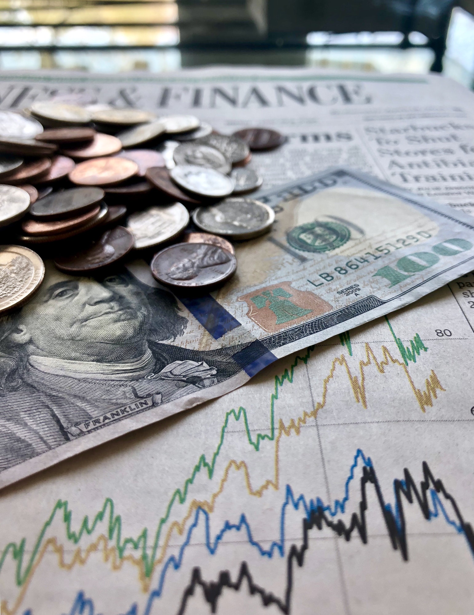 Money & Finances. Hundred dollar bill with coins on the news paper’s finances & stocks section.